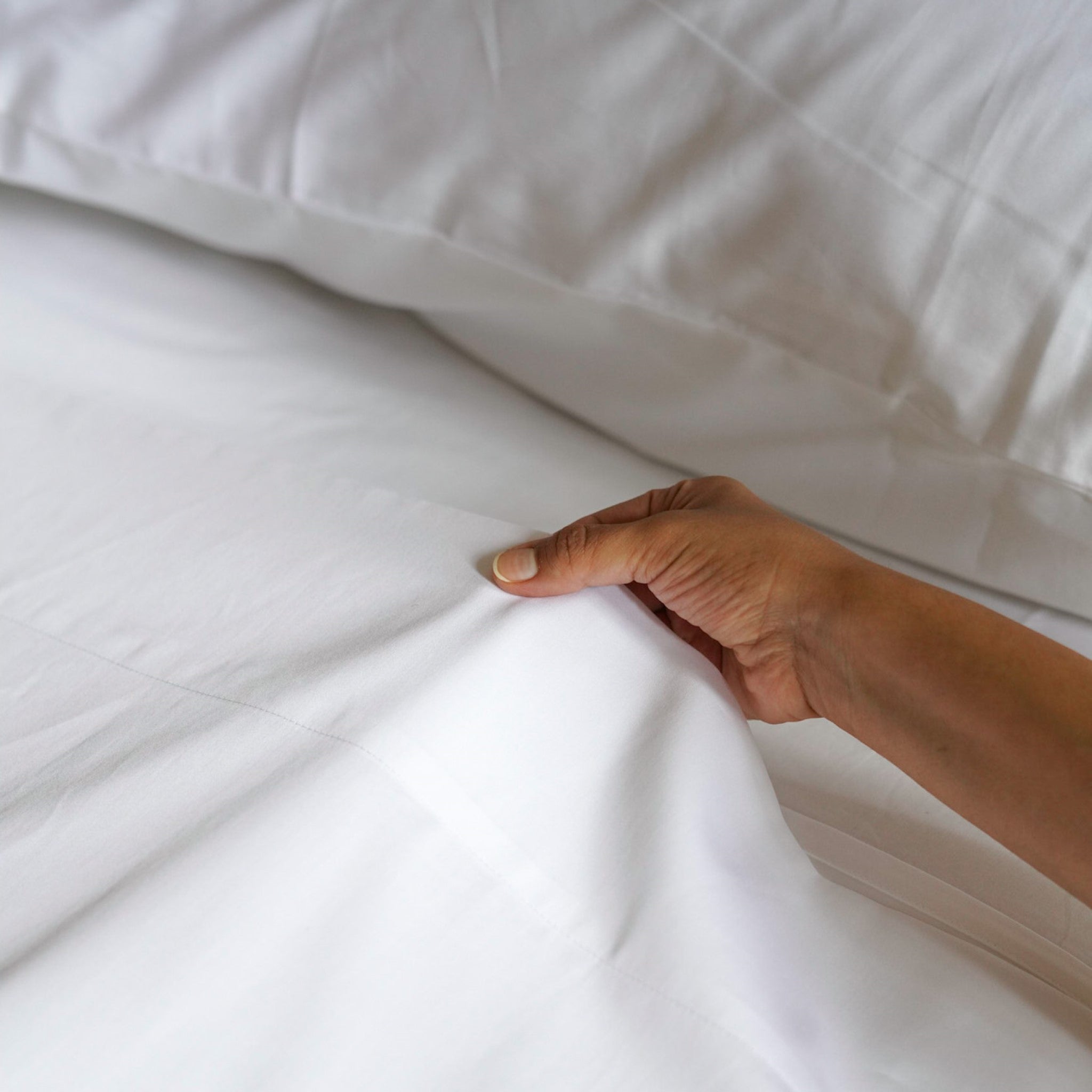 Homebird Organic Sateen Flat Sheet -model pulling at sheet #colour_white