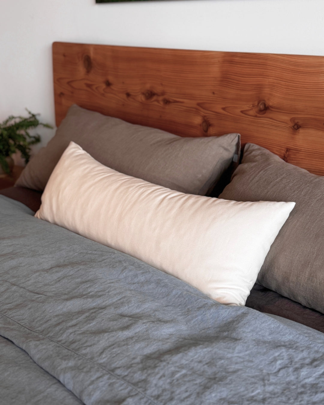 Kakun Lumbar Pillow - on bed with natural wood headboard
