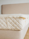 Kakun Luxury Wool Moisture Barrier - on mattress with strap over Kakun logo