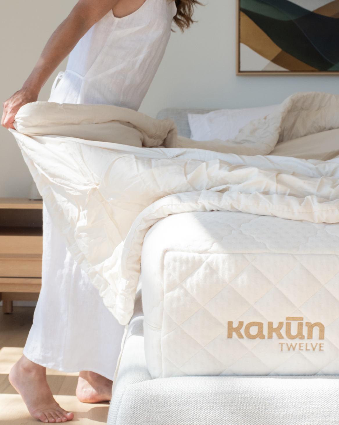 Kakun Twelve Organic Latex Mattress - logo showing at base with model adjusting organic comforter