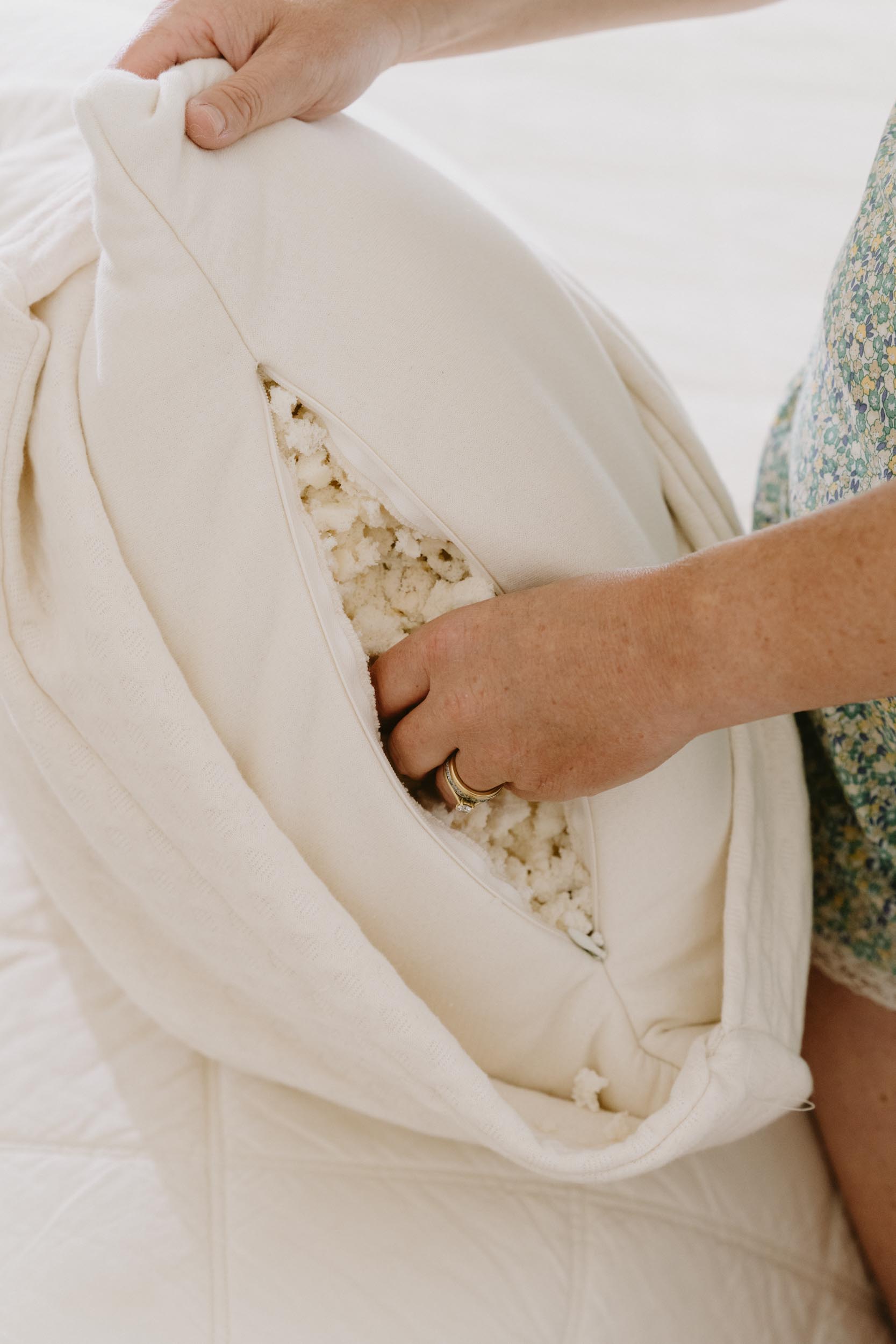 Woman reaching into unzipped kakun organic luxury head pillow and feeling organic shredded latex fill