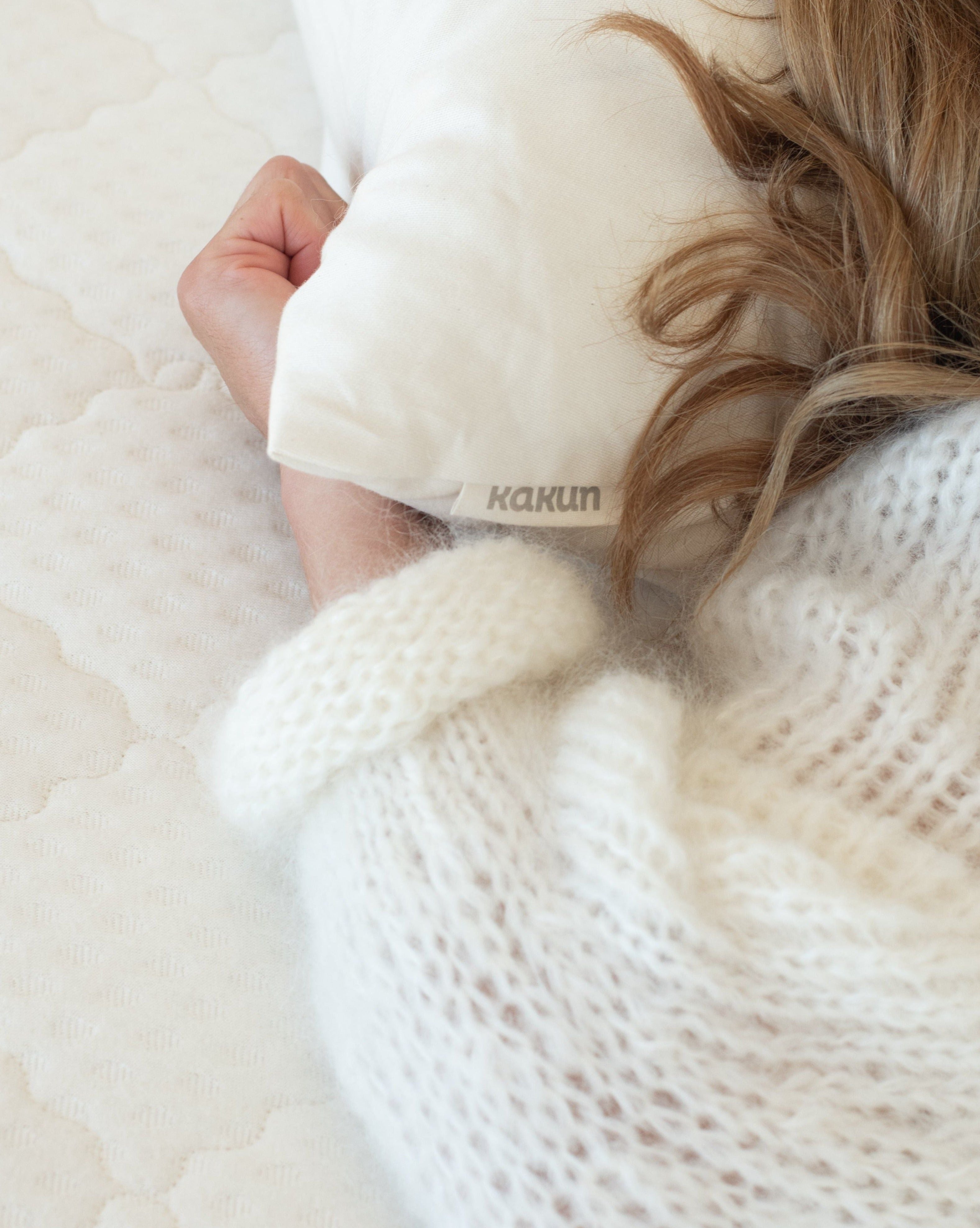 woman laying her head on organic Kakun wool head pillow while laying on a Kakun organic mattress