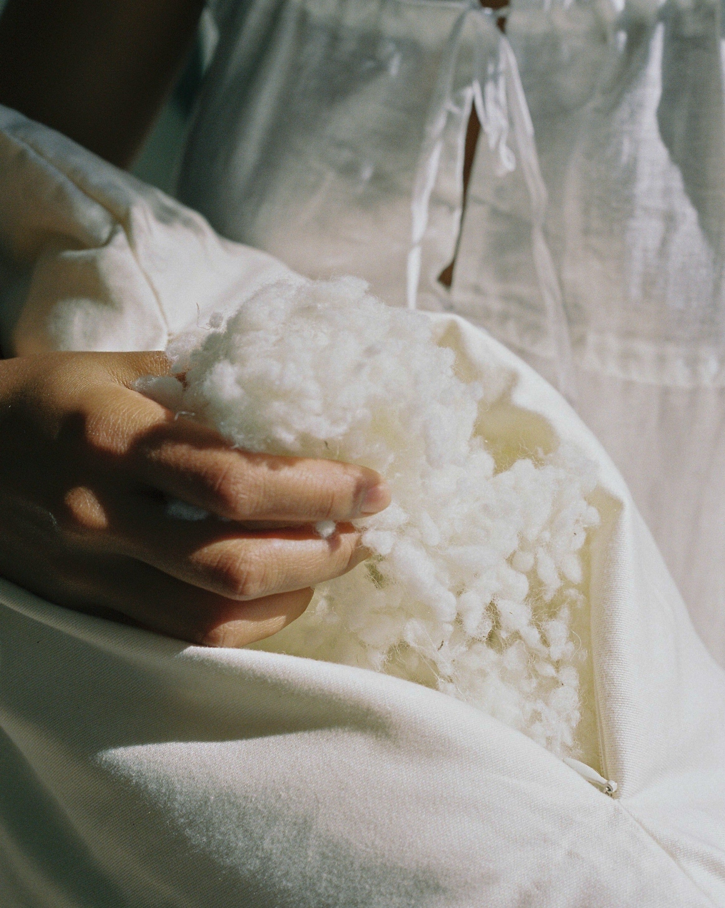 Woman pulling out organic wool pillow fill from unzipped kakun organic wool pillow