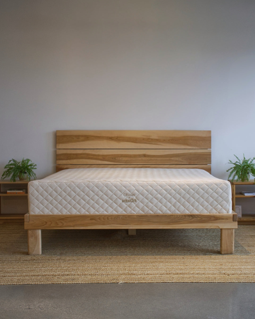 Wooden bed with an Obasan Kakun organic latex mattress in a minimalistic room.