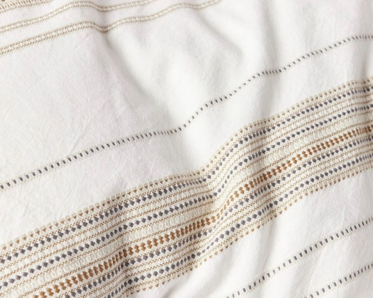 Lobos organic cotton duvet cover with yarn dyed stripes of small geometric patterns. Soft white with hazel. From Coyuchi.